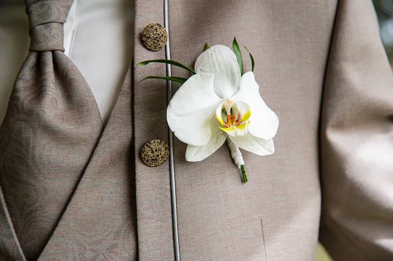 Détail du costume d'une marié avec une orchidée en boutonnière