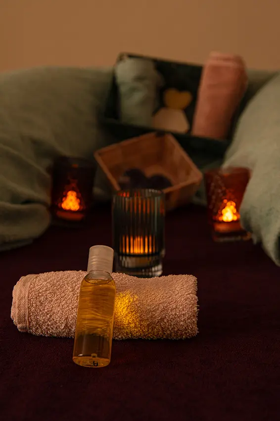 huile de massage, serviettes roulées avec petites bougies pour ambiance avant le massage